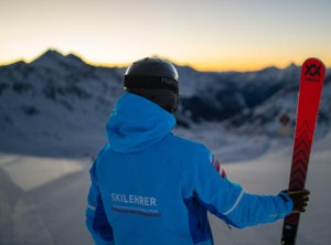 Skifahrer bei Sonnenuntergang mit Ski in der Hand